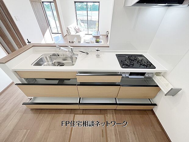 【キッチン】【キッチン収納】 対面式キッチンは白基調で清潔感たっぷり。食洗機・三口コンロ付きで家事効率◎。広々ワークトップと豊富な収納で、家族との会話も弾む快適な空間です。