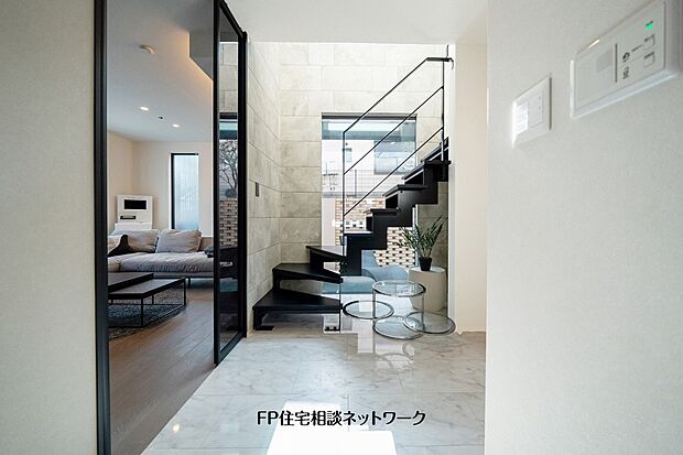 吹抜けと鉄骨階段が開放感を演出する玄関ホール。室内にいながら中庭とのつながりも感じられる設計です。