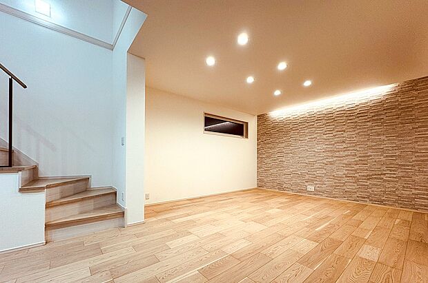 石目調のアクセントウォールを採用したリビング。間接照明が陰影をより映えさせ、上質な雰囲気に。（3号棟）