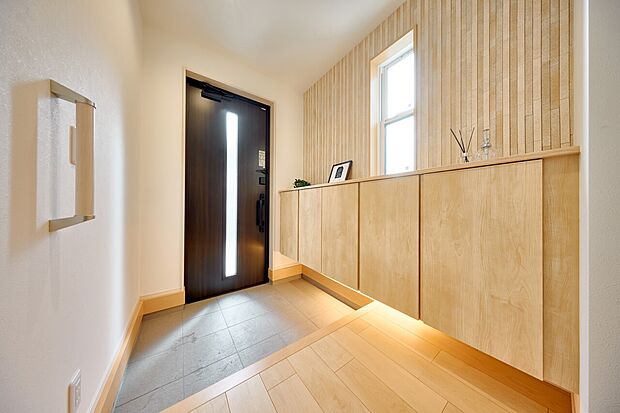 【玄関】アクセントウォールや間接照明を設え、お客様をお迎えする玄関の表情を豊かに彩ります。(5号棟)