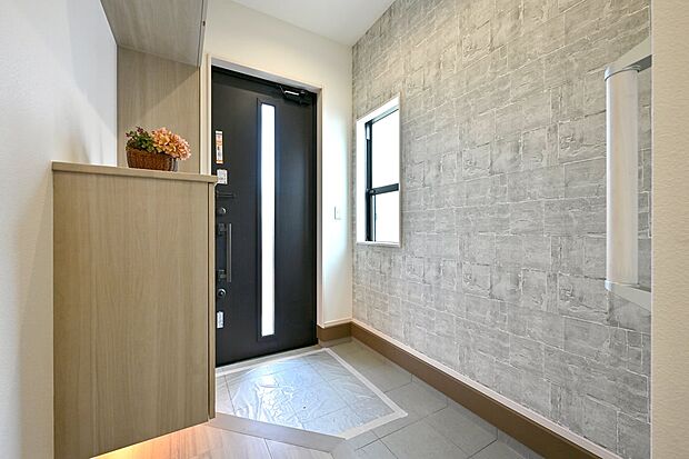 【玄関】アクセントクロスを施し、間接照明も調えました。お客様をお迎えする玄関の表情を豊かに彩ります。(1号棟)