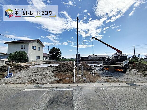 【現地外観写真】アスファルト舗装の前面道路（幅約4.7m）に面し、広々とした敷地は駐車3台分が可能で、周囲に住宅が点在する落ち着いた街並みです。完成予定は2026年12月。