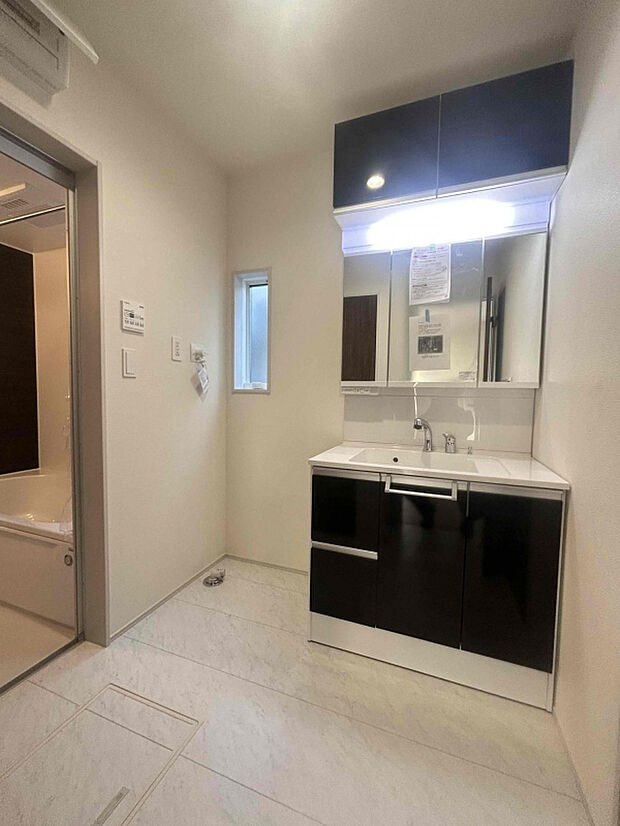 【【1号棟】】横幅が900mmワイドの三面鏡付きで朝の身支度もラクラク。吊り戸が付いている洗面台でたっぷり収納できます。