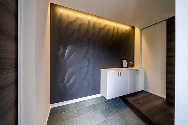【【本分譲地に建築可能な建物プラン例】】ブラックのアクセントクロスと間接照明が印象的な玄関ホール。訪れたゲストの印象に残る、ホテルライクな佇まいです。《分譲地外:建物面積101.25m2、建物価格2116万円》