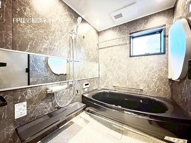 【上質さを極めたバスルーム】重厚なマーブル調パネルが上質さを演出するバスルーム。ゆったり浸かれるワイド浴槽と浴室暖房乾燥機を備え、一日の疲れを優雅に癒すくつろぎ空間。窓付きで換気も採光も確保した、機能美あふれる上質仕様です。