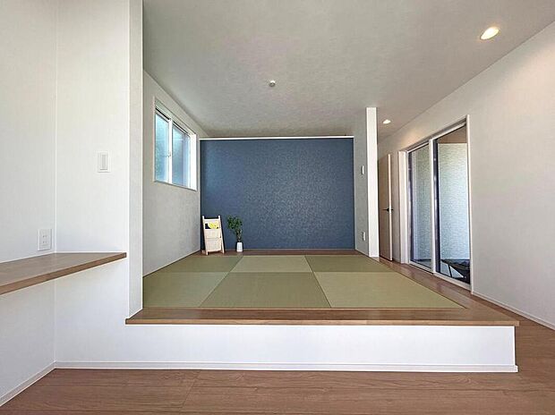 【【1号地/1階洋室(約10.0帖)】】洋室の一角に配置された、小上がりの畳コーナー。青いアクセントクロスが空間を彩ります。お昼寝や家事スペースなど、多用途にご活用いただけます。/2025年12月撮影