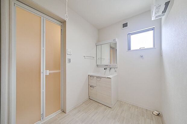 【洗面化粧台】広々とした洗面台には、三面鏡と引き出しを備えた充実の収納スペース。三面鏡の裏には、3cm刻みでトレーの高さを調整できる収納があり、スキンケア用品や小物をすっきりと整理できます。