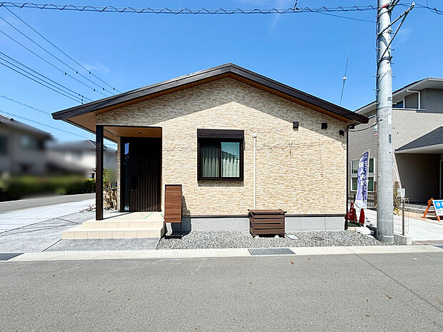 【9号棟外観】ゆったりとした玄関アプローチは、雨の日でも濡れにくく機能的。木目調のスタイリッシュな宅配ボックス付きポストや、室外機カバーなど、生活感を感じさせない細やかな外構の工夫が、住まいの美しさを高めています。