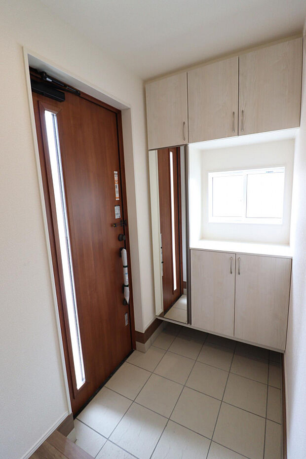 【【玄関/2号棟】】小窓から自然光が差し込む、明るい玄関。姿見付きの玄関収納は、土間部分のお手入れがしやすいフロートタイプです。