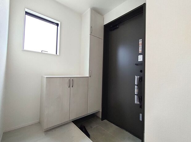 【玄関スペース(1号棟)】玄関には収納を備え、靴や外出用品をすっきり整理可能。小窓から光が差し込む明るい空間で、来客時の印象も良好。使いやすさと美しさを兼ね備えた、快適なエントランスです♪