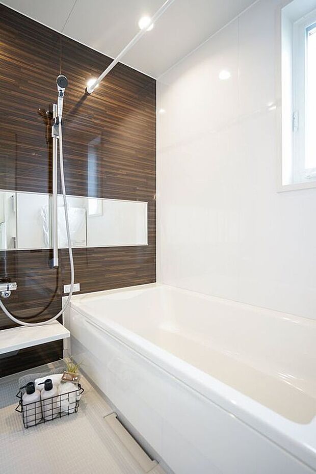 スタイリッシュなダークブラウンのアクセントパネルが印象的な浴室。ワイドミラーが空間に奥行きをもたらし、広々とした印象を与えます。