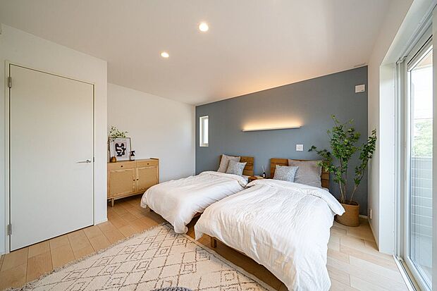 【寝室】11号地の約9.7帖の主寝室は、ベッドを2台置いても余裕の広さ。シックな色合いのアクセントクロスに、柔らかい間接照明が素敵な空間です。