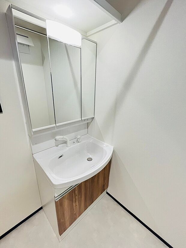 【洗面室】洗面台はシンプルで使いやすいデザインです。収納スペースも備えられていて日常のアイテムを整頓しやすい仕様です。明るい色合いのため洗面所全体がすっきりとした印象です。鏡も広く使い勝手に配慮されています。