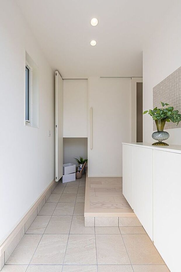 【玄関】■8号地玄関　L字型の玄関は、ご家族が同時に靴の脱ぎ履きがしやすく、動きが重ならないゆとりある動線を確保。階段下を活かした土間クロークも備え、靴や外出用品をすっきりまとめられます。