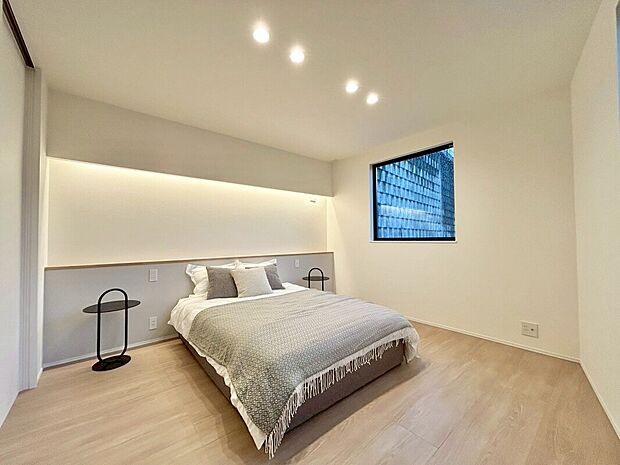 【リビング以外の居室(2号地)】間接照明が優しく包み込む、洗練された寝室。毎日の疲れを癒し、上質な眠りへと誘うプライベート空間。明るい木目調の床と白い壁が都会的な雰囲気を演出。