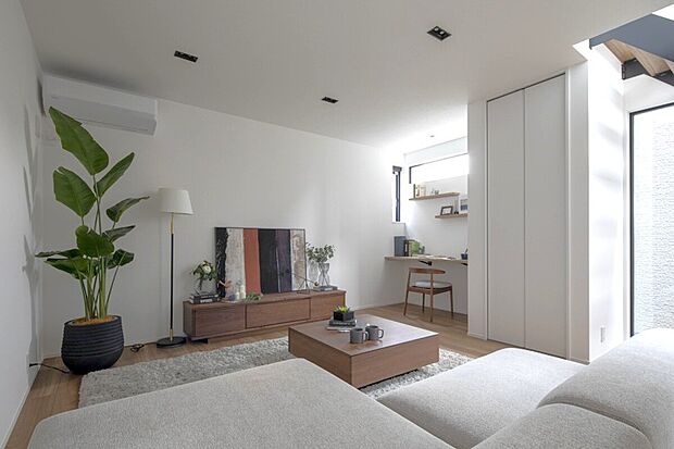 【2号地内観】心地よい陽光がLDKを満たす、洗練された空間。温もりある木目調家具が家族の時間を彩り、併設のワークスペースで毎日がもっと充実する住まいです。