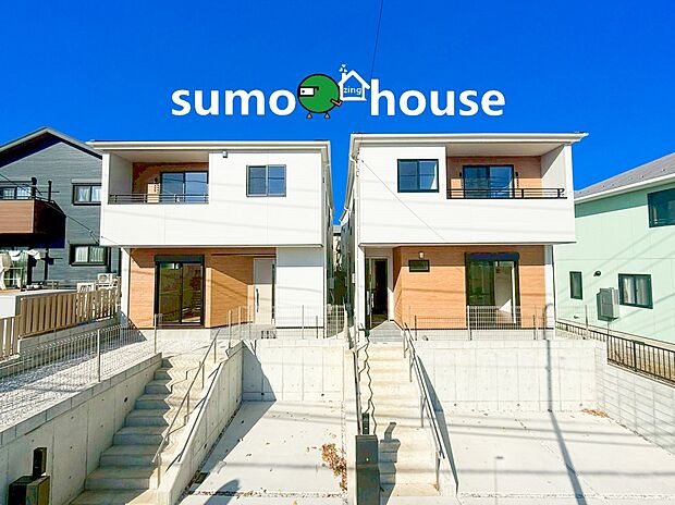 爽やかな青空の下、建物は白を基調に温かみのある木目調のアクセントを組み合わせたモダンなツートンカラーで統一されています。