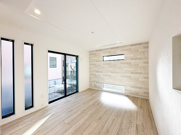 明るい木目調のフローリングに、上品なアクセントクロスが映える洗練された空間 。縦長のスタイリッシュなスリット窓や地窓を効果的に配置することで、外からの視線を遮りながら豊かな採光を確保しました 。