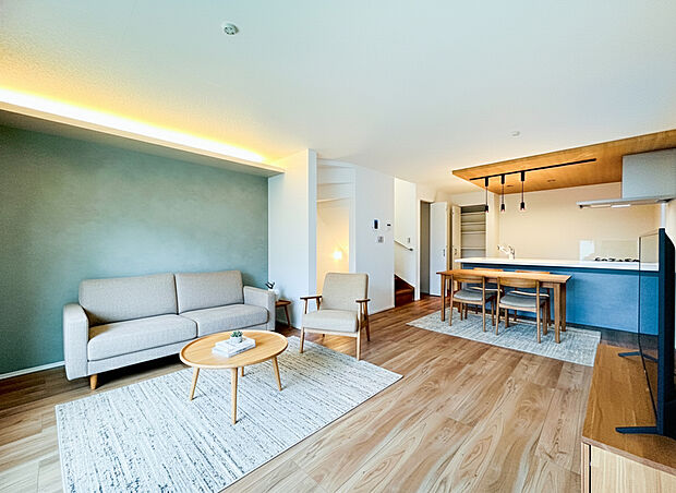 美しい木目調のフローリングと、スケルトン階段の木の質感が調和し、温かみのある空間を演出。キッチン側の天井には間接照明も配され、家族が自然と集まる、洗練された憩いの場です。