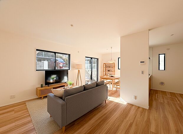 南向きの大きな窓からたっぷりと光が入り、日中は照明いらずの明るさです 。温かみのある木目調のフローリングが光を優しく反射し、家族が自然と集まりたくなるような心地よい空間を演出 。