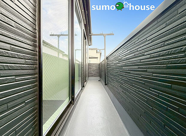 外壁には重厚感のあるダークトーンのアクセントパネルを採用し、スタイリッシュで落ち着いた空間を演出しています。プライバシーを確保しながらも、開放的な空を感じられる広々としたバルコニーです。