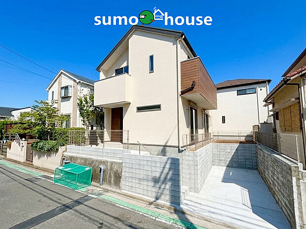 モダンで洗練されたフォルムが目を引くこだわりの新築住宅です。南側に大きなスペースを確保することで抜群の陽当たりと風通しを実現しました。玄関周りの木目調アクセントが温かみを添え家族を優しく迎え入れます。