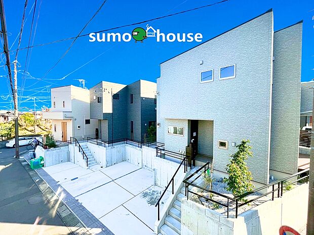 【洗練されたデザイン】明るいホワイトの外壁が、街並みに上質な印象を与えます。高低差を活かした広々カースペースと、手すり付きで安全に昇降できるアプローチが魅力。機能美を兼ね備えた、新生活のステージです。