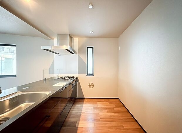 【キッチン】黒のワークトップが映えるキッチンと、温もりのある木目調フロアが織りなす、モダンで上質なLDKです。二面に配された窓からは豊かな自然光が差し込み、奥行きのある開放的な空間を演出します。