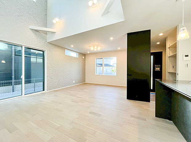 【リビング】吹き抜けとアクセントクロスが創り出す、ハイセンスな大空間！ 淡い色調のフローリングと質感豊かな壁が調和し、モダンで落ち着いた雰囲気を演出。