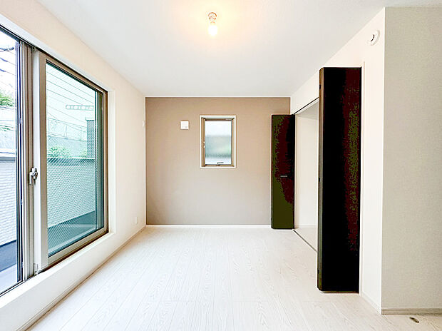 【洋室】大きな掃き出し窓からたっぷりの自然光が入る、明るく開放的な洋室。一面のアクセントクロスが部屋に深みと洗練された雰囲気を与えます。