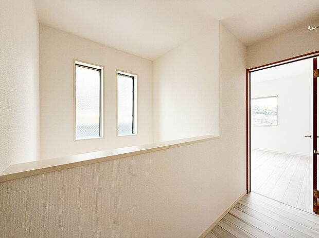 【玄関吹抜け】玄関から階段にかけて採用された吹き抜けが、圧倒的な開放感を演出します 。高い位置に設けられたスリット窓からは優しい自然光が差し込み、家全体を明るくクリーンな印象に 。