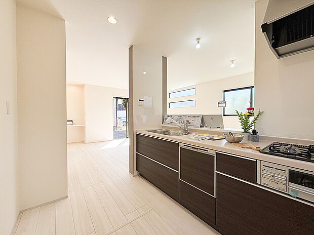 【キッチン】リビング全体を見渡せる対面式キッチンは、お料理中も家族とのコミュニケーションを大切にできる設計です 。シックなダークトーンのデザインが空間を引き締め、毎日の家事をスタイリッシュに演出します。