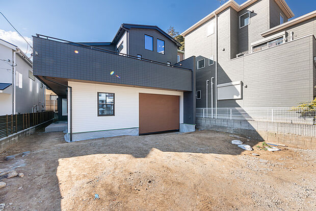 ダークトーンの外壁が空に映えるスタイリッシュな邸宅。広大な敷地と並列駐車可能なカースペースが、ゆとりある暮らしを叶えます。