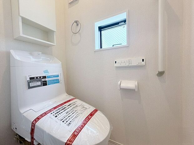 【トイレ】清潔感あふれる高機能トイレです。換気や採光に便利な小窓に加え、トイレットペーパー等の保管に重宝する壁面収納付き。手すりやタオル掛けも標準装備されており、使いやすさにこだわった空間です。
