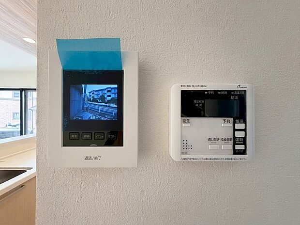 【TVモニター付きインターホン・リビング　給湯器】来客時に相手の顔が確認できて防犯面も安心なTVモニター付きインターホン。隣には、リビングにいながらスイッチ一つでお風呂の沸かし直しや予約ができる、便利な給湯器リモコンも設置されています。
