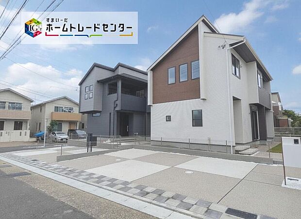 【現地外観写真】モダンな全2棟の建物が並び、広い舗装道路とゆとりある駐車スペース（3台想定）で車の出入りも快適。落ち着いた色調が周囲になじみ、陽だまりのある暮らしが想像できます。