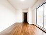 寝室：バルコニーへと繋がる大きな掃き出し窓から、心地よい光と風をたっぷり採り込める明るい寝室。深みのあるフローリングが落ち着いた雰囲気を演出し、奥には大容量のウォークインクローゼットを完備しています。