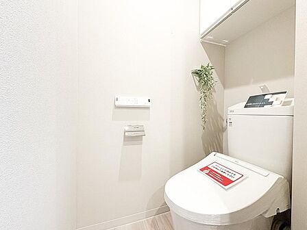 白を基調とした清潔感あふれるレストルーム。上部にはトイレットペーパー等を隠して収納できる便利な吊戸棚を完備。温水洗浄機能付きで毎日快適にお使いいただけます。