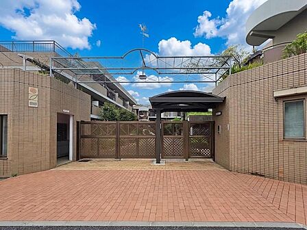 エントランス前にはゆとりあるアプローチが設けられ、建物内へと続く動線が整えられています。周囲を囲むタイル貼りの外壁や門扉が住まいの独立性を高め、低層レジデンスらしい落ち着いた雰囲気を感じる共用部です。