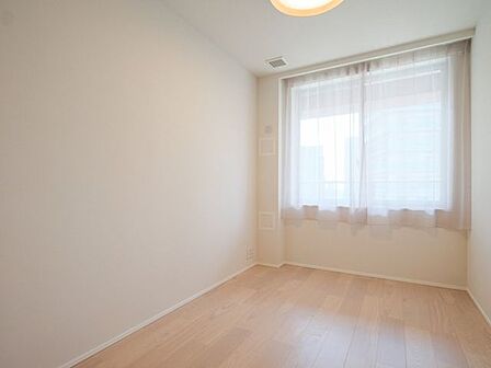 腰高窓を備えた洋室2です。明るい色合いのフローリングと白を基調とした内装が調和し、家具の配置もしやすいシンプルな空間です。
