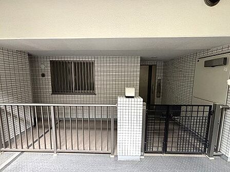 タイル張りの壁面と整えられたフェンスが調和し、プライバシーに配慮された落ち着きのある玄関まわりです 