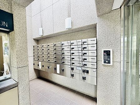 重厚感のある石目調の壁面と機能的な集合ポストが調和する、落ち着いた佇まいのエントランスです