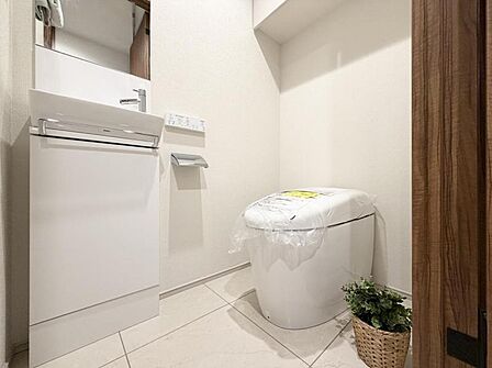 【トイレ】見た目もスマートなタンクレストイレ。白のタイルを基調とした高級感のあるトイレ空間。