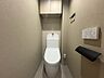 トイレ：落ち着いた色調で統一された清潔感のあるトイレ空間です。上部の収納棚が、すっきりとした空間を保ちます。