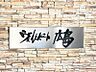 エントランス：温かみのある石積みの壁に、モダンなデザインの看板が調和。訪れる人を優しく迎え入れるエントランスです。