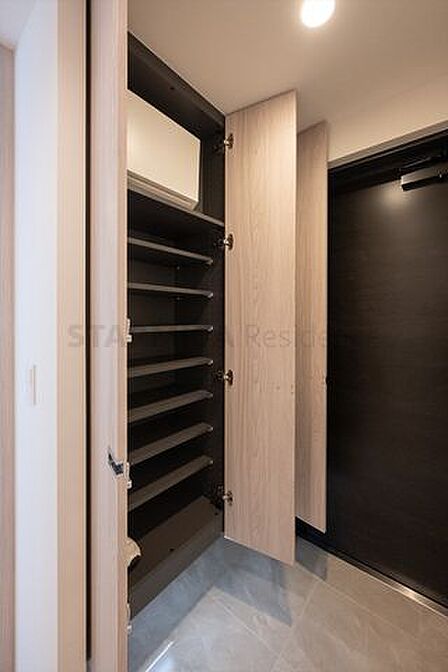 可動式の棚なのでサイズ変更も自由自在の下足入れ。鍵などの小物を収納できるトレイや、リュック型の防災グッズも備わった、住まう人を考えた贅沢なひと空間です。