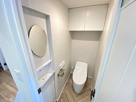 快適なタンクレスシャワートイレです。扉付きの収納と棚があるのでトイレットペーパーなどスッキリ収納できそうですね。自動洗浄手洗い器と鏡付き!床がリビングとは違う木目でお洒落です!