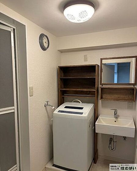 【木の質感が心地よい洗面室】温かみのある木製フレームの鏡と収納棚をカスタマイズ。洗濯機置場上部にも便利な棚があり、タオルや洗剤もスッキリ。毎日の身支度が楽しくなる空間です。