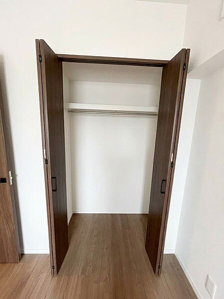 扉を開けた収納スペースです。内部に棚とハンガーパイプを備えています。