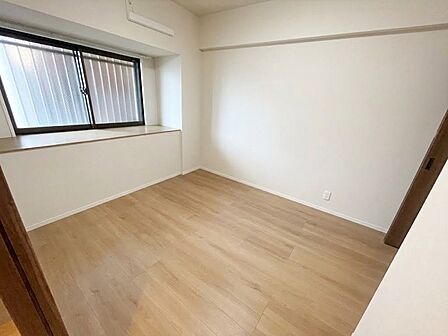 窓を備えた洋室です。白い壁面と木目調の床でまとめられています。
